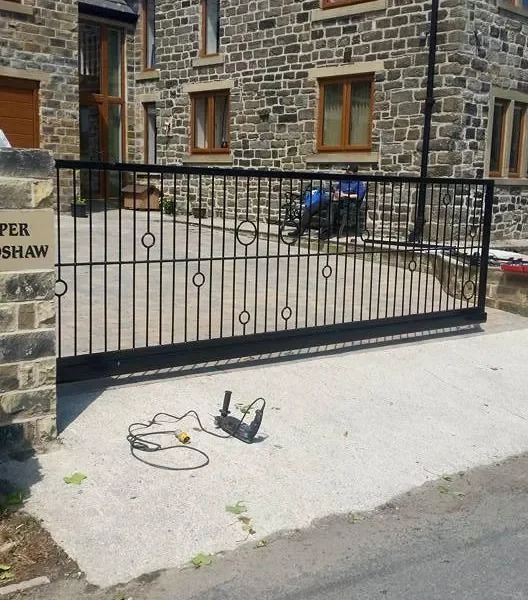 Black steel railing running the length of a stone property driveway