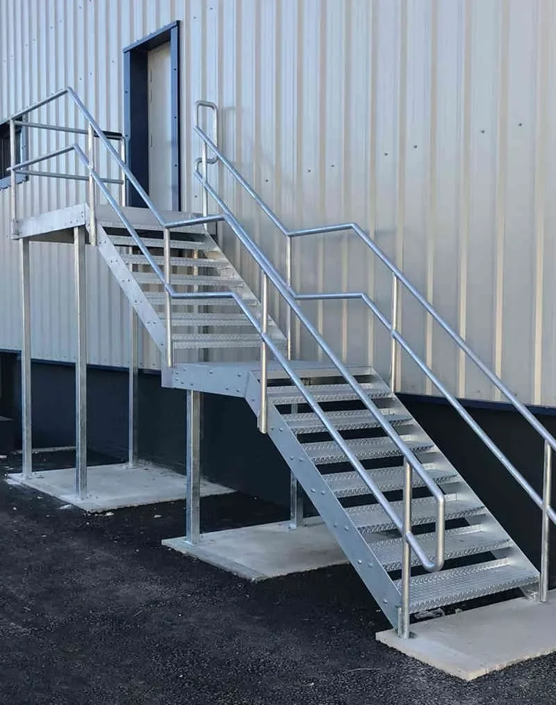 Galvanised external fire escape staircase fixed to white profile cladding