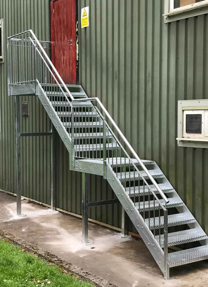 Galvanised steel fire escape staircase on a green clad industrial unit