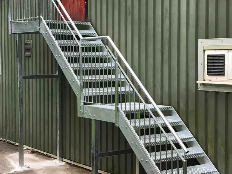 Galvanised steel fire escape staircase on a green clad industrial unit