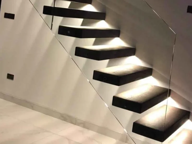 Illuminated cantilever floating staircase with dark steel treads