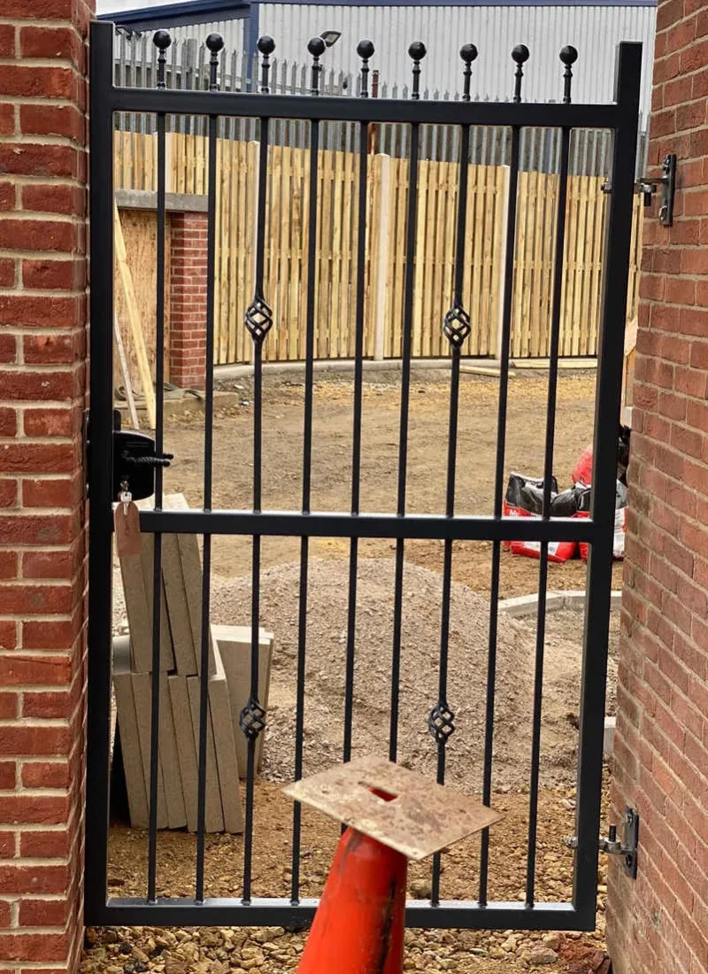 Black wrought iron gate set into a brick wall