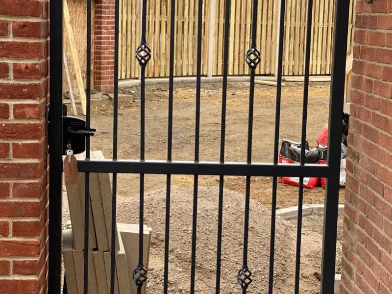 Black wrought iron gate set into a brick wall